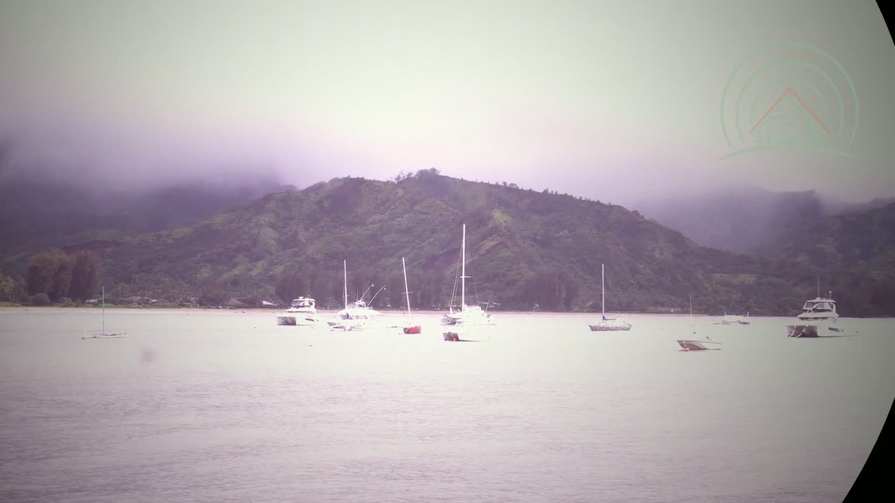 Sailboats at anchor in Hanalei Bay below mist-wrapped green mountains